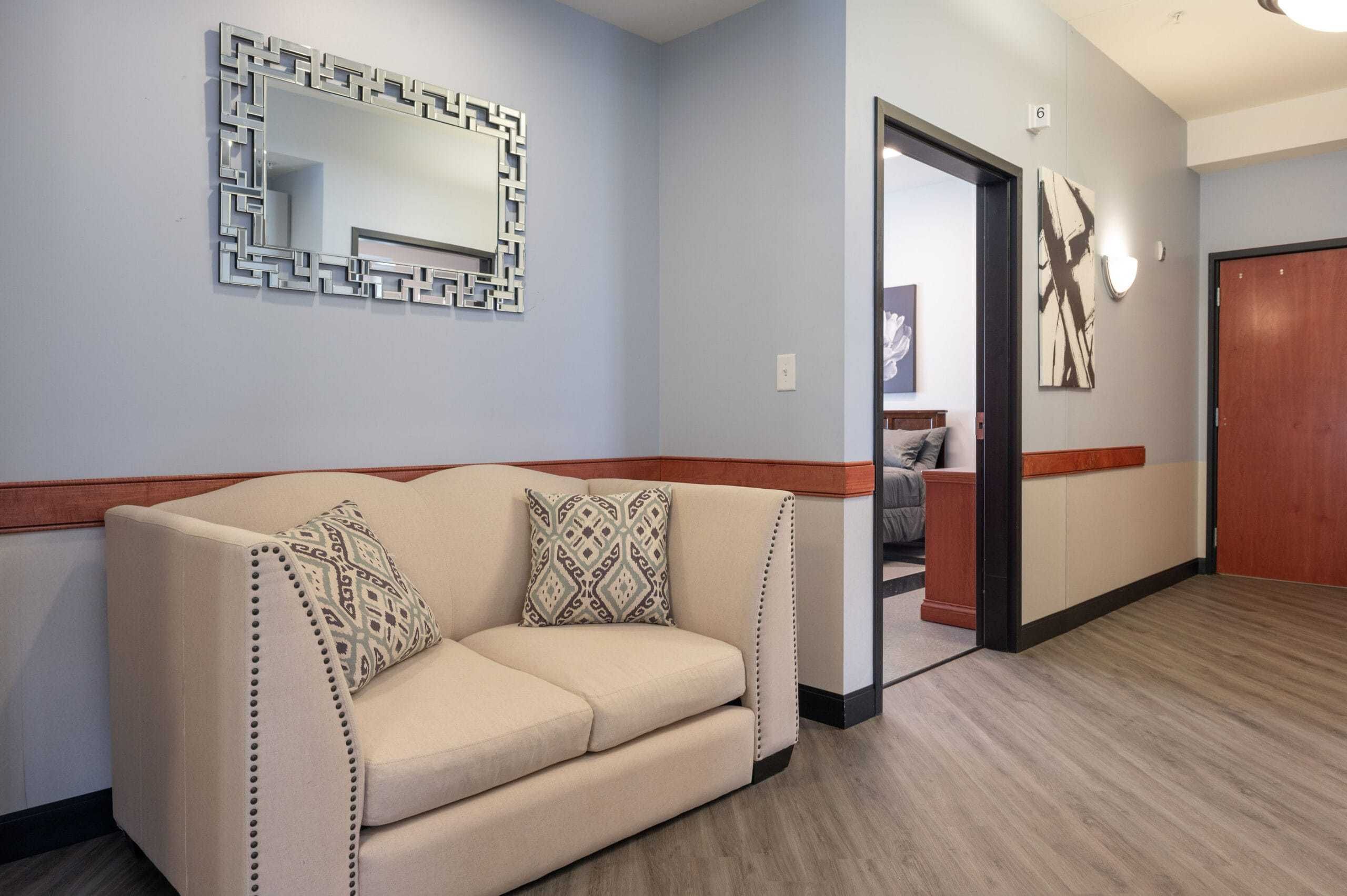 couch in hallway next to bedroom at inpatient rehab
